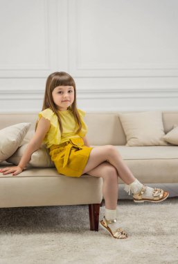 Kız kanepelerde oturuyor.