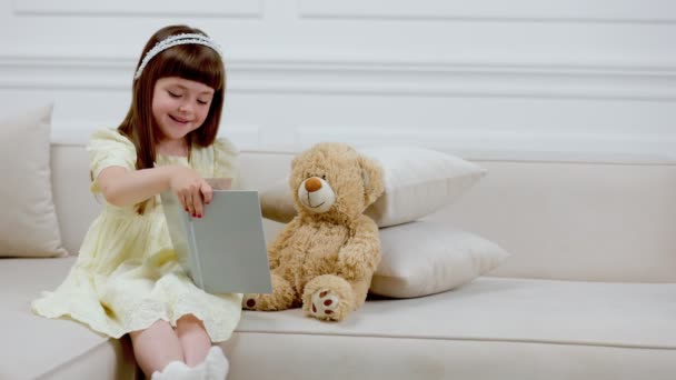 Menina com ursinho de pelúcia lendo um livro — Vídeo de Stock