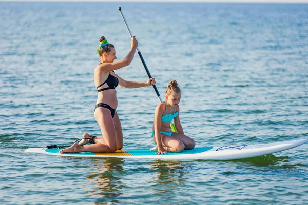 Mamá y su hija flotan en el agua en el tablero — Foto de Stock