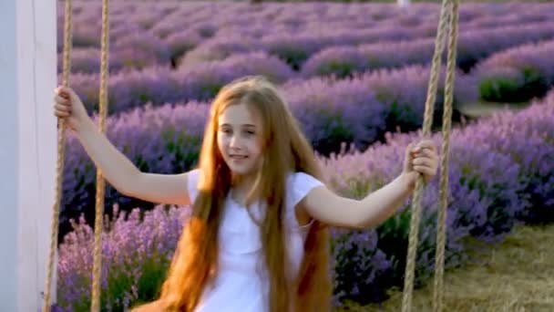 Flicka rida en gunga i en lavendel fält — Stockvideo