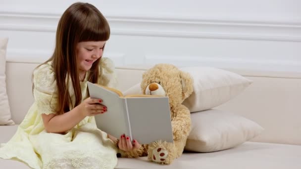 Menina com ursinho de pelúcia lendo um livro — Vídeo de Stock