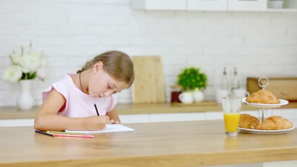 台所に座っていると女の子が絵を描く — ストック動画