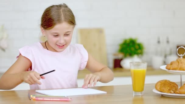 Dívka kreslí, zatímco sedí v kuchyni — Stock video