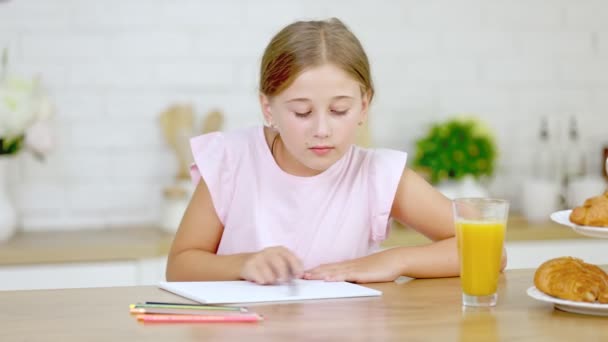 Dívka kreslí, zatímco sedí v kuchyni — Stock video