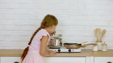 Kız tencerede ne olduğunu kokluyor.