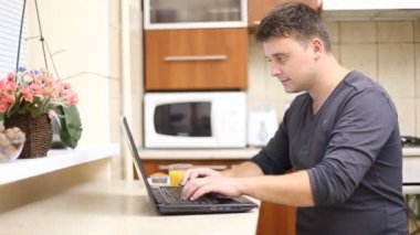 adam mutfakta bir dizüstü bilgisayar ile