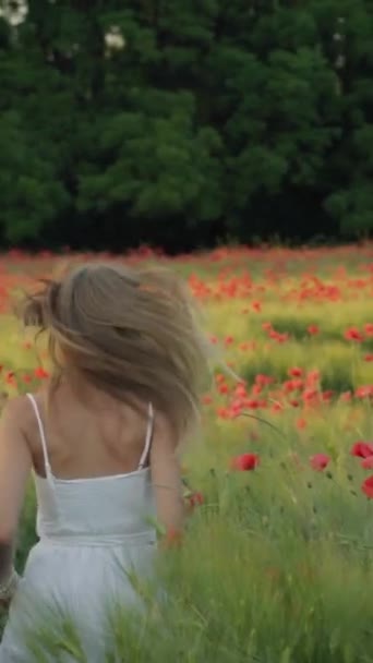 Uma menina em um vestido branco corre em um campo florescente. Orientação vertical — Vídeo de Stock
