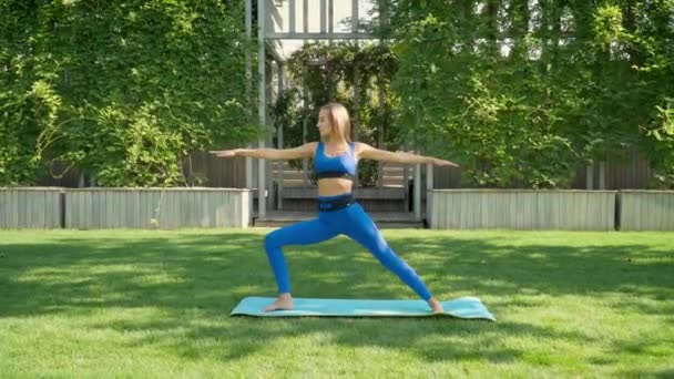 Yoga no parque. Mulher loira em sportswear praticando ioga Vídeos De Bancos De Imagens Sem Royalties