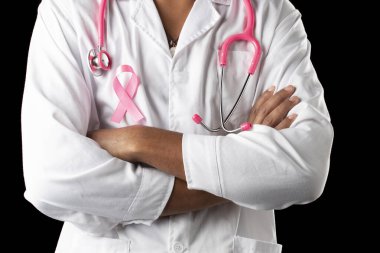 Siyah arka planda pembe steteskop ve pembe farkındalık göğüs kanseri kurdelesiyle koyu tenli bir doktor..