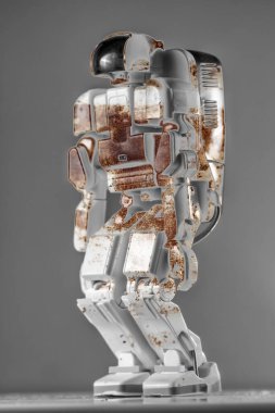 Gri bir arka planda paslı modern otonom robot oyuncağı.