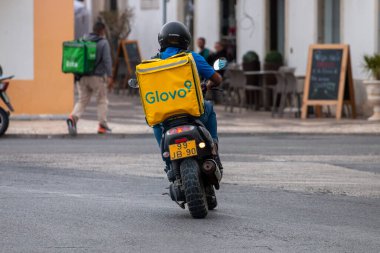 FARO, PORTUGAL - 20 Haziran 2021: Portekiz, Faro sokaklarında motosikletli Glovo kuryesi.