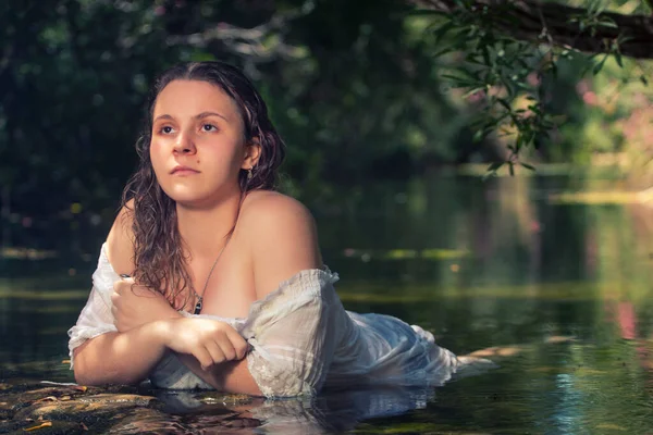 在溪水边穿着白色衣服的年轻貌美女子 — 图库照片