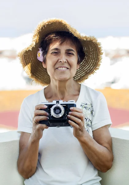 Mulher madura segurando uma câmera fotográfica vintage — Fotografia de Stock