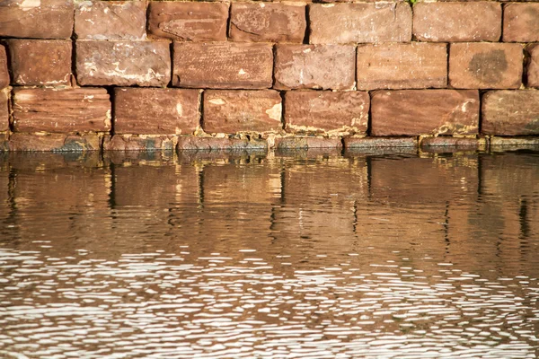 Ziegelsteinmauer von einem Gebäude, das eine Reflexion auf dem Wasser erzeugt — Stockfoto