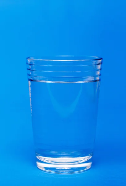 Vidro de água sobre um fundo azul — Fotografia de Stock