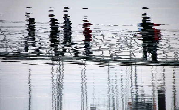 Reflexion von Menschen verzerrt auf dem Wasser auf den Docks — Stockfoto