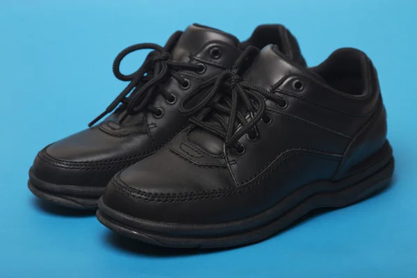 Zwarte schoenen geïsoleerd op een blauwe achtergrond — Stockfoto