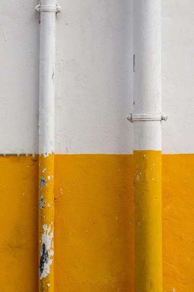 Połowa pomalowane w kolorze żółtym i białym z rury na ścianie. — Zdjęcie stockowe