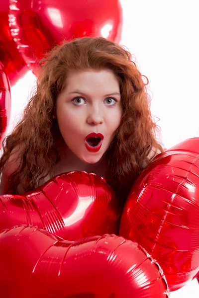 Glückliches junges Mädchen zwischen roten Luftballons — Stockfoto