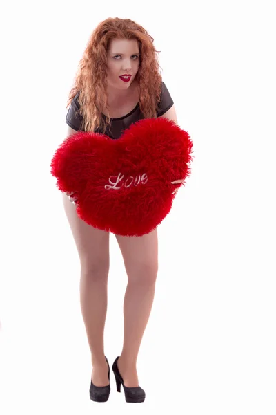 Feliz chica joven con una almohada de corazón rojo — Foto de Stock