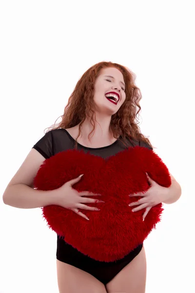 Feliz chica joven con una almohada de corazón rojo — Foto de Stock