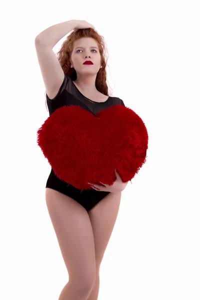 Feliz chica joven con una almohada de corazón rojo — Foto de Stock