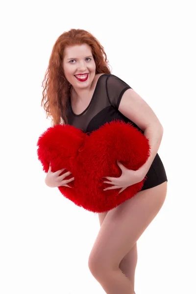 Genç kızla mutlu bir kırmızı kalp yastık — Stok fotoğraf