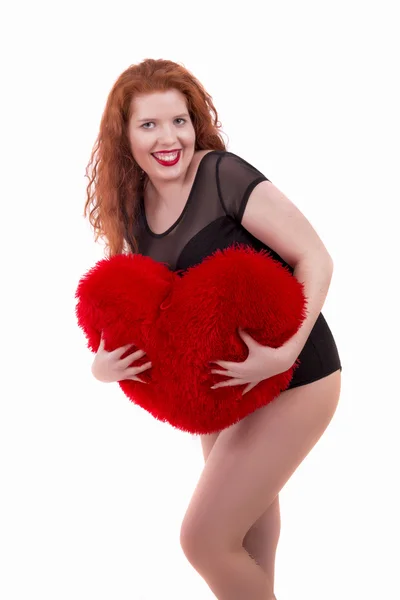 Feliz chica joven con una almohada de corazón rojo — Foto de Stock