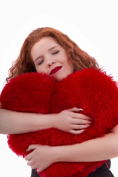 Feliz chica joven con una almohada de corazón rojo — Foto de Stock