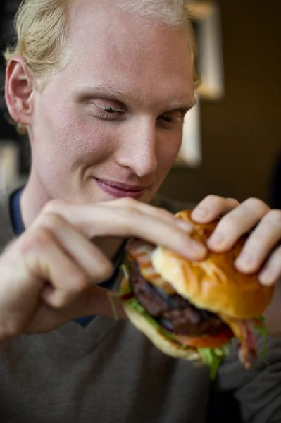 Νεαρός άνδρας που τρώει μεγάλο μπιφτέκι — Φωτογραφία Αρχείου