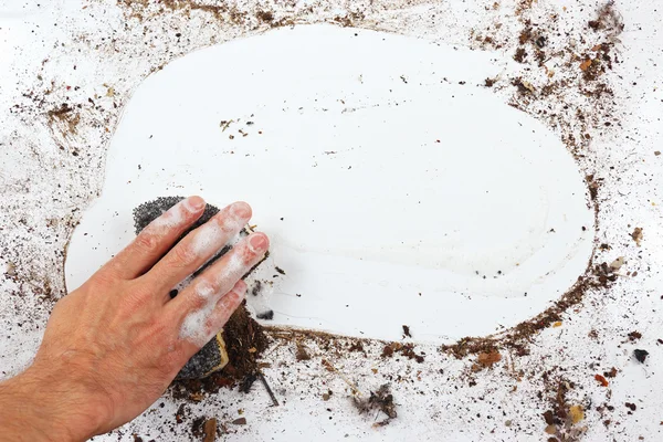 Hand with wet black sponge cleans dirty surface