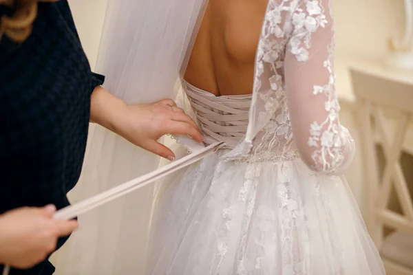 結婚式の日には 新婦付添人はウェディングドレスを着るのに役立ちます 強調は 白いウェディングドレスのボタンを固定する手にあります 新郎に会うために花嫁を準備する — ストック写真
