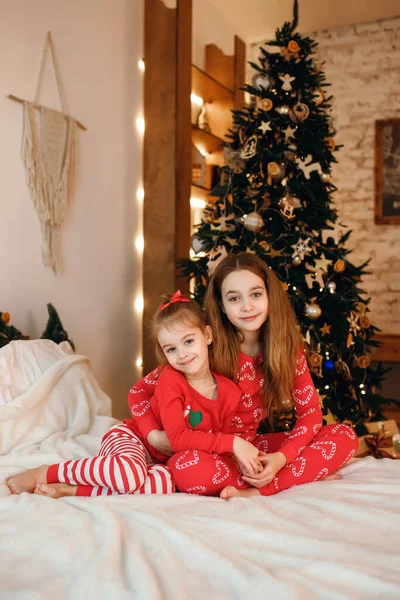 Två Söta Små Systrar Röd Pyjamas Sitter Sängen Och Kramas — Stockfoto