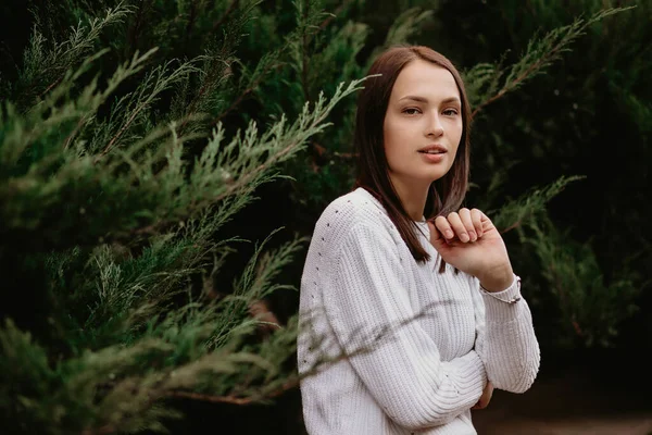 Ardıç süren esmer bir kızın portresi. Parktaki bir fotoğrafçıya poz veren güzel bir genç kadın bitkilerin dallarına yaslanıyor. Kız beyaz bir kazak giyiyor. Metin için boş alan