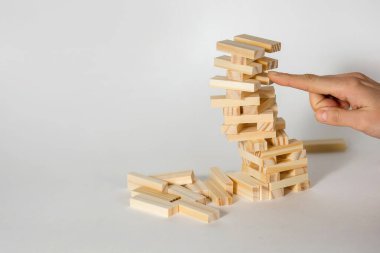 Beyaz arka planda tahta masa oyunu. İnsanlar, dengenin önemli olduğu bir şans oyunu oynar. Tahta blok kulesi ağır eğildi ve çökmek üzere. Metin için boş alan