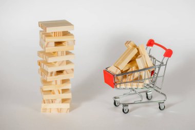 Beyaz arka planda tahta masa oyunu ve tahta bloklu küçük bir araba. Gayrimenkul inşaatı ve inşaat malzemeleri satın alma kavramı. Denge ve çevikliğin önemli olduğu bir oyun