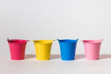 Beyaz arka planda dört tane renkli oyuncak kovası. Sarı, mavi, pembe ve kırmızı kova yan yana duruyor. Gelecekteki yenileme kavramı ya da hasat ya da ekin ekmeye başlama