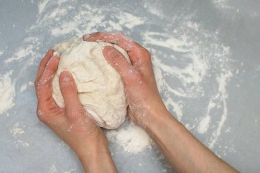 Mutfakta bir kadın evdeki gri bir masaya hamur yoğuruyor. Erkek eli hamur yoğurmak için yoğurur. Metin için boş alan. DIY tüm aile için yemek hazırlama