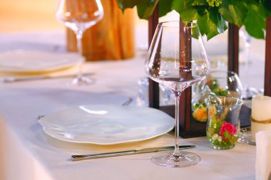 Restoranda bir sehpa, bir bardak şarap, bir tabak ve gümüş çatal bıçak. Restorandaki bir masa ek olarak çiçekler ve ahşapla süslenir. Metin için boş alan