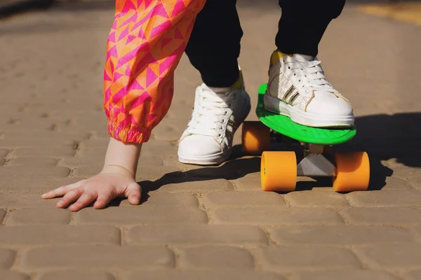 顽固不化的孩子在公园里学习骑绿色滑板或铅笔板 一个活泼的少年骑着滑板摔了一跤 手放在地上 — 图库照片