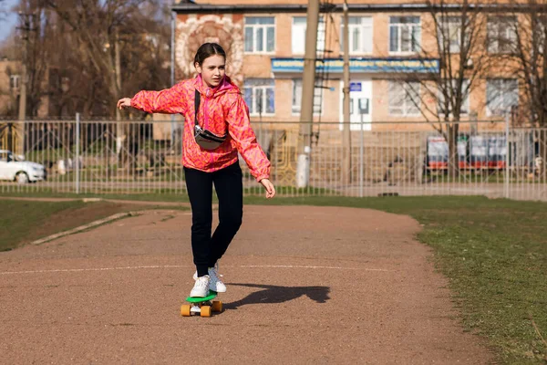 明るい服の10代の女の子が公園でスケートボードやペニーボードに乗っています スケートボードはあなたの健康と調整を改善するための素晴らしい方法です テキストのためのフリースペース — ストック写真