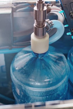 Santraldeki otomatik bir hatta suyun üretimi ve arıtılması. Durulama, temizleme ve suyla doldurma için otomatik sistem. Yakın çekim - temiz suyla dolu plastik şişe