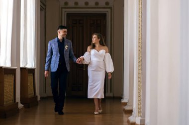 Gelin ve damat el ele tutuşup birbirlerine bakıyorlar. Düğünlerinde yakışıklı damat ve zarif gelin. Kutlama zamanı gelinlik giymiş yeni evliler.