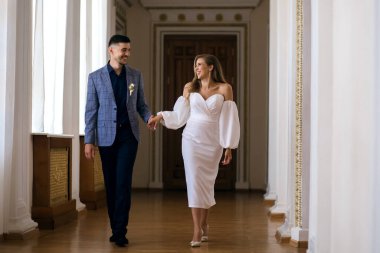 Gelin ve damat el ele tutuşup birbirlerine bakıyorlar. Yakışıklı damat ve akıllı gelin düğün günlerini kutluyorlar. Heteroseksüel yeni evli çift