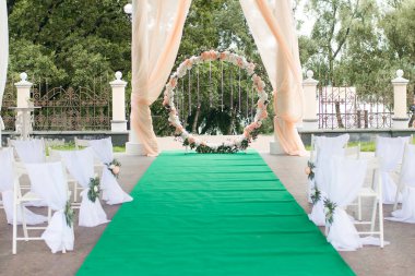 Düğün seremonisi için yuvarlak düğün kemeri ve gelin ve damat için yeşil halılı kristal kolyeler. Geleneksel düğün töreni. Düğün töreni için mükemmel bir dekor.