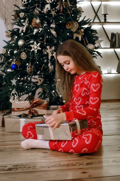 Ein Kleines Mädchen Roten Pyjama Sitzt Neben Einem Geschmückten Weihnachtsbaum — Stockfoto