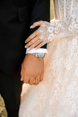 Gelin ve damat çifti. Sıcak ve güneşli bir günde alyanslarını gösteren zarif gelin ve damadın yakın çekimleri. Aşk, düğün ve romantik bir çift. Mutlu, yeni evli çift açık havada.