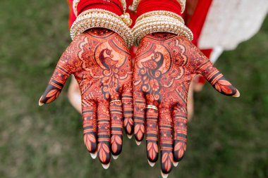 Karmaşık kına desenleriyle süslenmiş bir kadının elleri. Hint mehendi tasarımlı genç kadın avuçları kültürel mirası ve geleneksel bayramları, düğünleri, özel etkinlikleri simgeliyor.