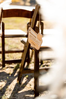 Aile tabelaları için ayrılmış ahşap bir iskemleye asılmış, sıcak güneş ışığına yakalanmış, samimi ve zarif bir tören atmosferi yaratıyor.