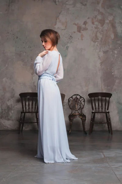 Uma menina em um vestido longo, olhando sobre seu ombro Fotografia De Stock